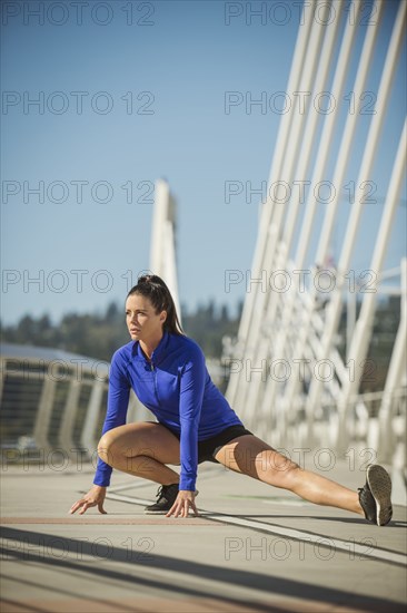 Caucasian woman stretching on urban bridge