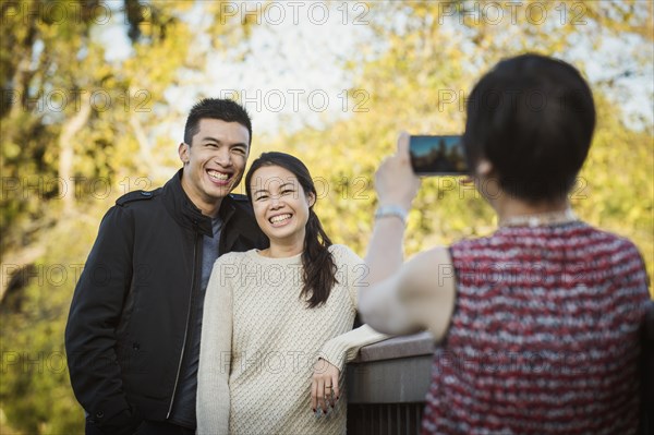 Chinese mother photographing adult offspring outdoors