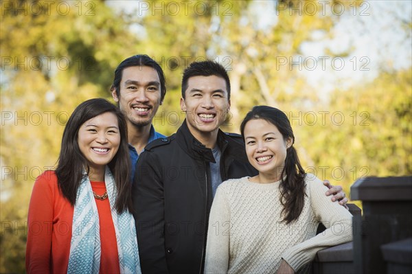 Adult Chinese siblings smiling outdoors