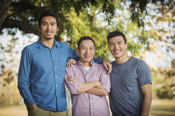 Chinese father and sons smiling outdoors