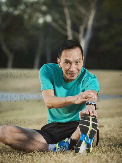 Older Chinese man stretching in park