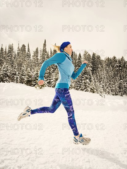 Caucasian woman running in snowy landscape