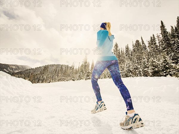 Caucasian woman running in snowy landscape