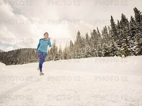 Caucasian woman running in snowy landscape