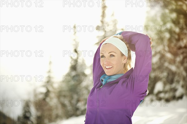 Caucasian woman stretching in snow