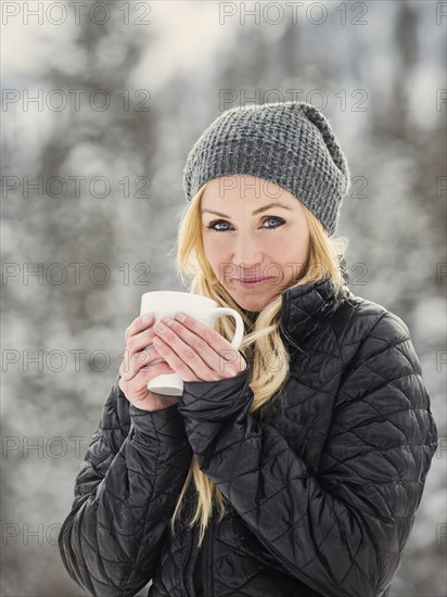 Caucasian woman drinking coffee in snow