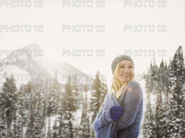 Caucasian woman wrapped in sweater in snow