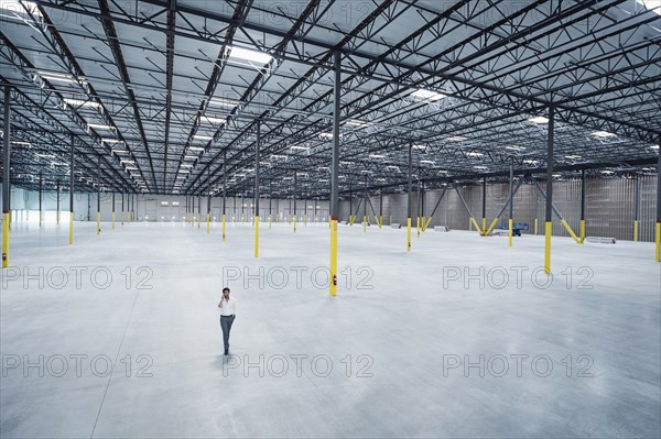 Indian businessman talking on cell phone in empty warehouse