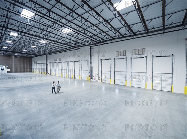 Businessmen walking near loading docks in empty warehouse