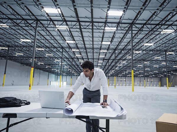 Indian architect using laptop in empty warehouse