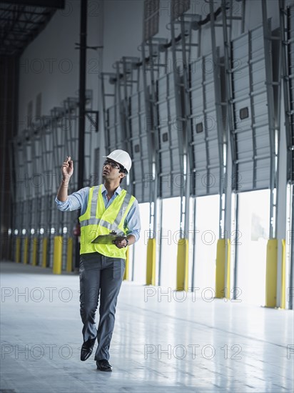 Indian worker carrying clipboard near open loading dock doors