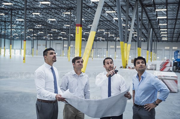 Architects examining blueprint in empty warehouse