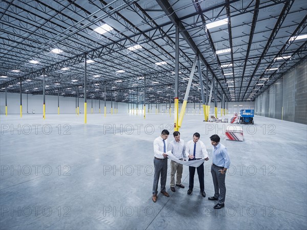 Architects examining blueprint in empty warehouse