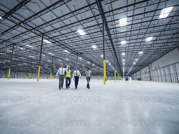 Businessmen walking and talking in empty warehouse