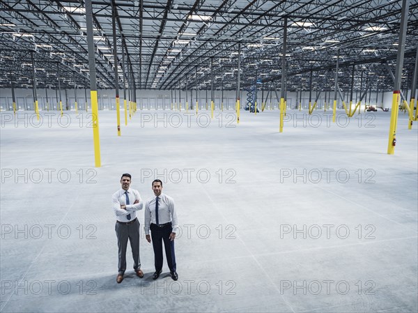 Smiling businessmen posing in empty warehouse