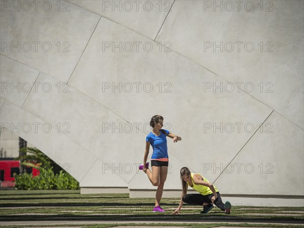 Caucasian women stretching legs near architecture