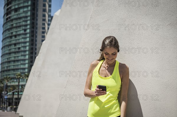 Caucasian woman leaning on wall texting on cell phone