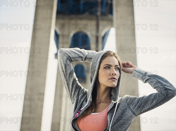 Caucasian woman stretching arms under overpass