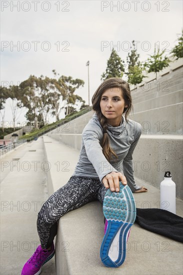 Caucasian woman stretching leg on stadium staircase