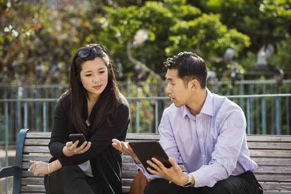 Chinese business people using technology on city bench