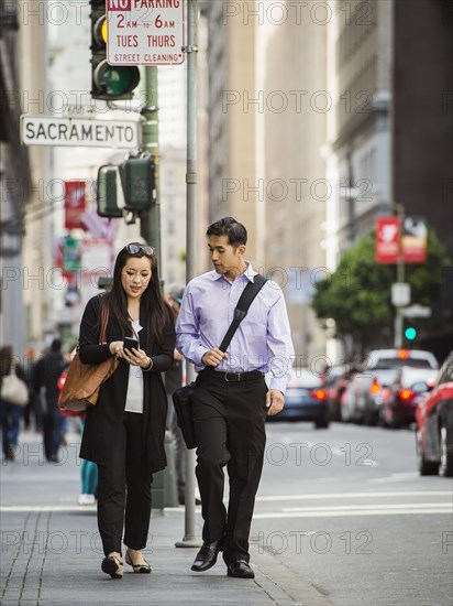 Chinese business people in city texting on cell phone