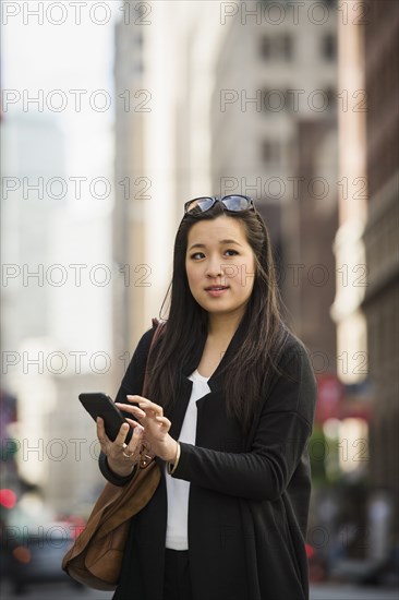 Chinese businesswoman texting on cell phone in city
