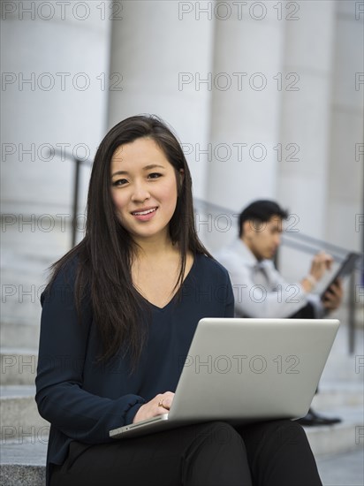 Chinese businesswoman sitting on staircase using laptop
