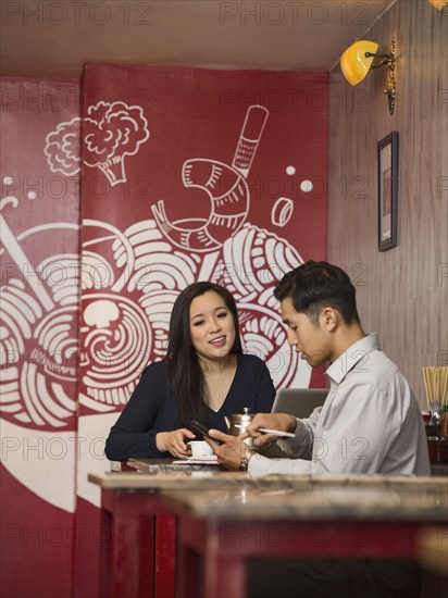 Chinese business people texting on cell phone in restaurant