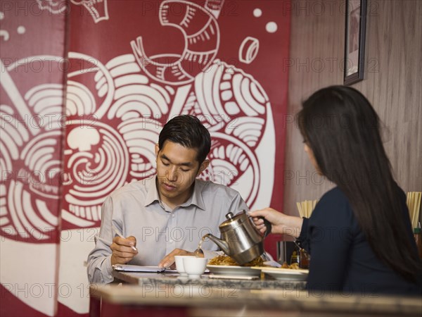 Chinese woman pouring tea in restaurant