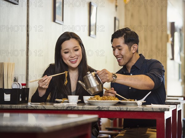 Chinese man pouring tea for woman in restaurant