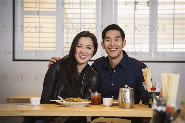 Smiling Chinese couple hugging in restaurant