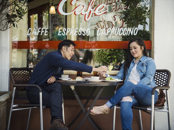 Chinese man tasting food of woman at outdoor cafe