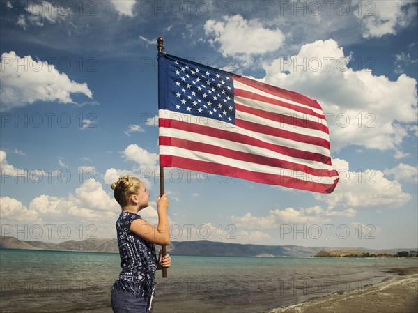 Caucasian girl holding American flag at beach