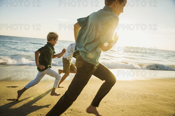 Caucasian brothers running on beach