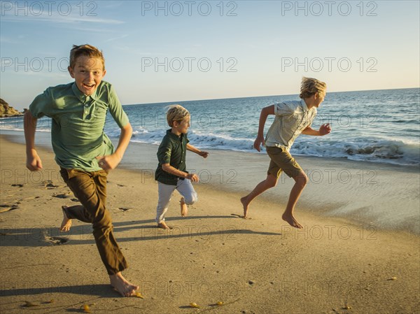 Caucasian brothers running on beach