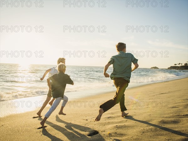 Caucasian brothers running on beach