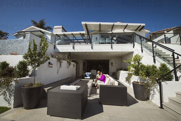 Older couple using digital tablet on modern backyard patio