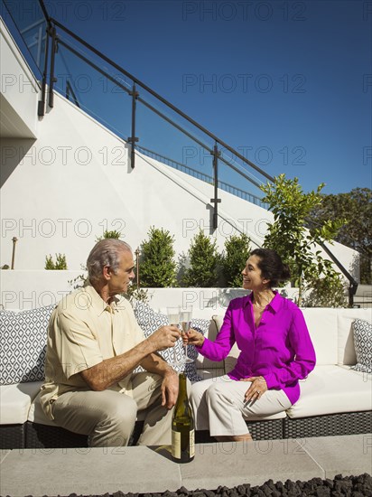 Older couple toasting on modern backyard patio