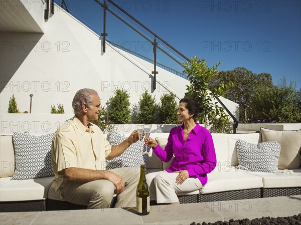 Older couple toasting on modern backyard patio