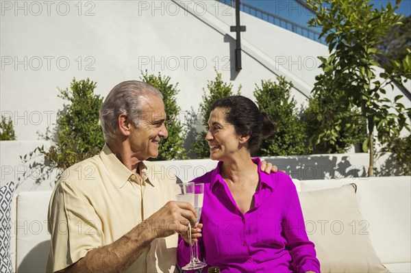 Older couple toasting on modern backyard patio