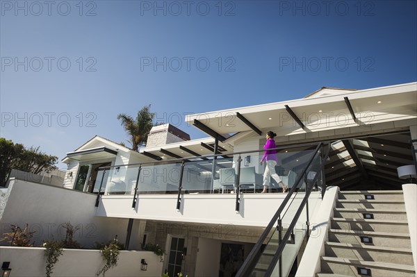 Hispanic woman walking on modern balcony