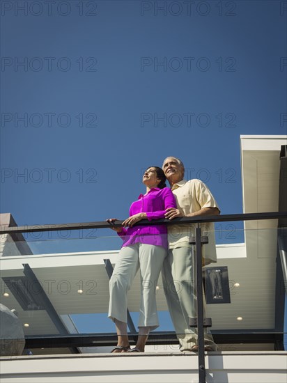 Smiling couple standing on modern balcony