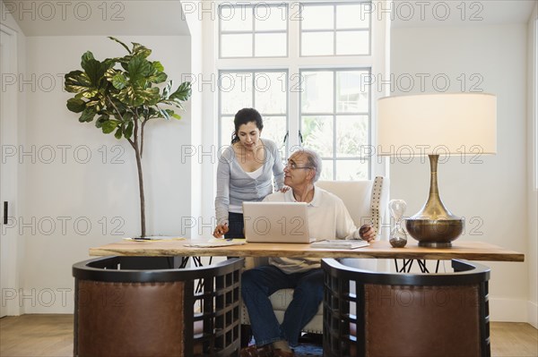 Older couple using laptop in home office