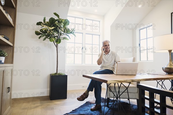 Caucasian man talking on cell phone in home office