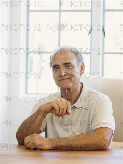 Portrait of Caucasian man holding eyeglasses at table