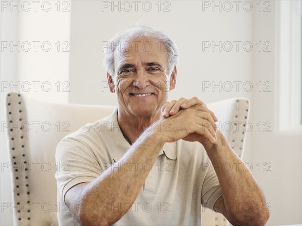 Portrait of Caucasian man with hands clasped at table