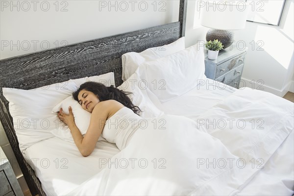 Hispanic woman sleeping in bed