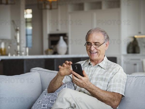 Caucasian man sitting on sofa texting on cell phone