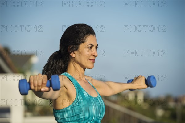 Hispanic woman lifting weights outdoors