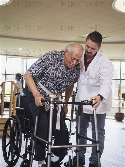 Physical therapist helping man in wheelchair use walker